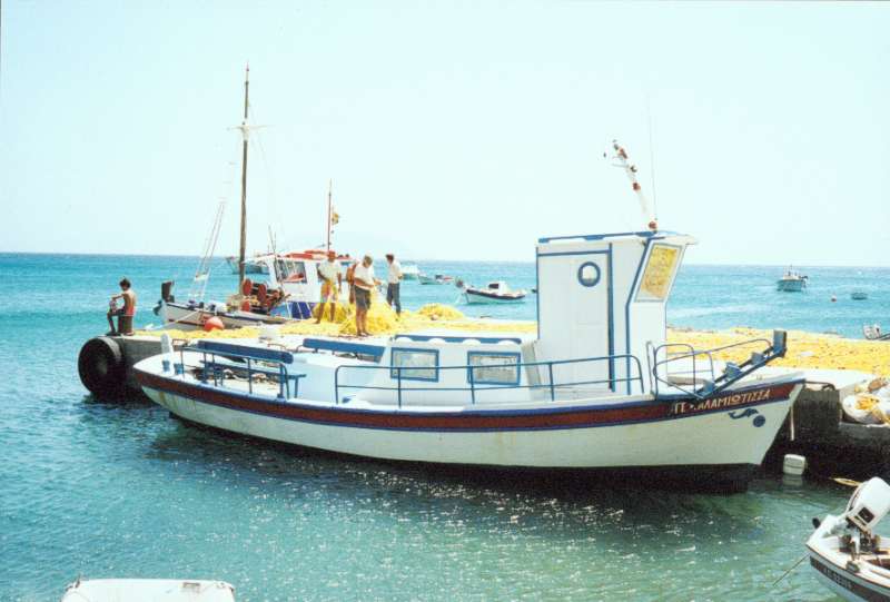 35. Η βάρκα Παναγία Καλαμιώτισσα που κάνει τακτικά δρομολόγια στις παραλίες του νησιού. Στο βάθος οι ψαράδες στεναχωρημένοι που δεν έβγαλαν τίποτα από τα δίχτυα τους.